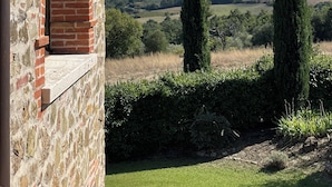 A stone building with a brick archway and a view of rolling hills and tall cypress trees. - Villa Tiberini Wine Relais (Torrita di Siena)