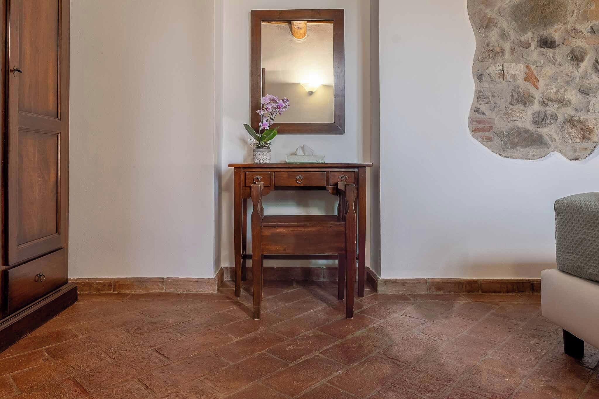A wooden desk with a mirror, a vase with flowers, and a tissue box.