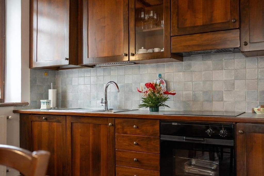 Een keuken met houten kastjes, een betegelde achterwand, een roestvrijstalen spoelbak en een vaatwasser.