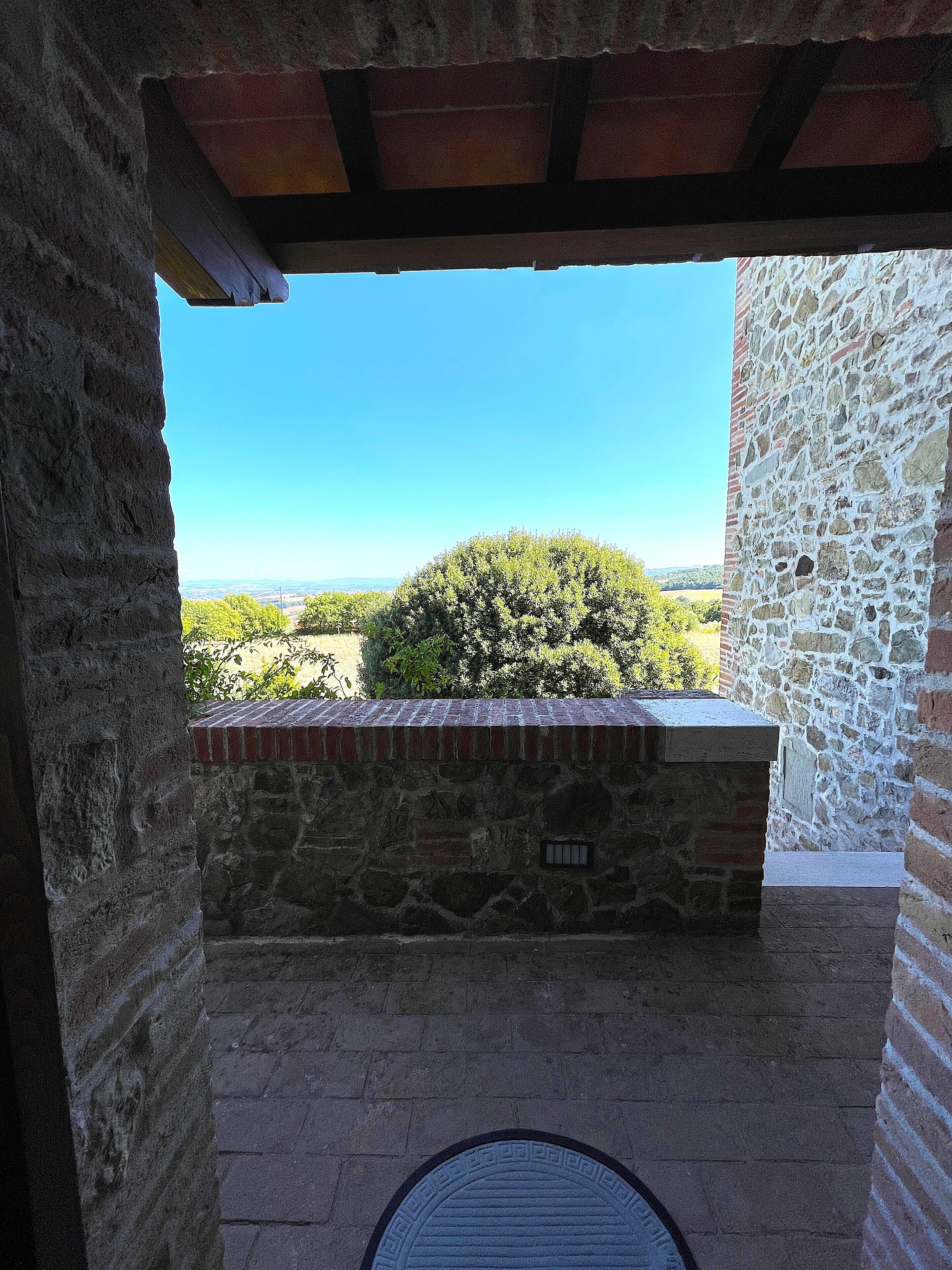 A stone wall with a view of a green landscape and a clear blue sky.