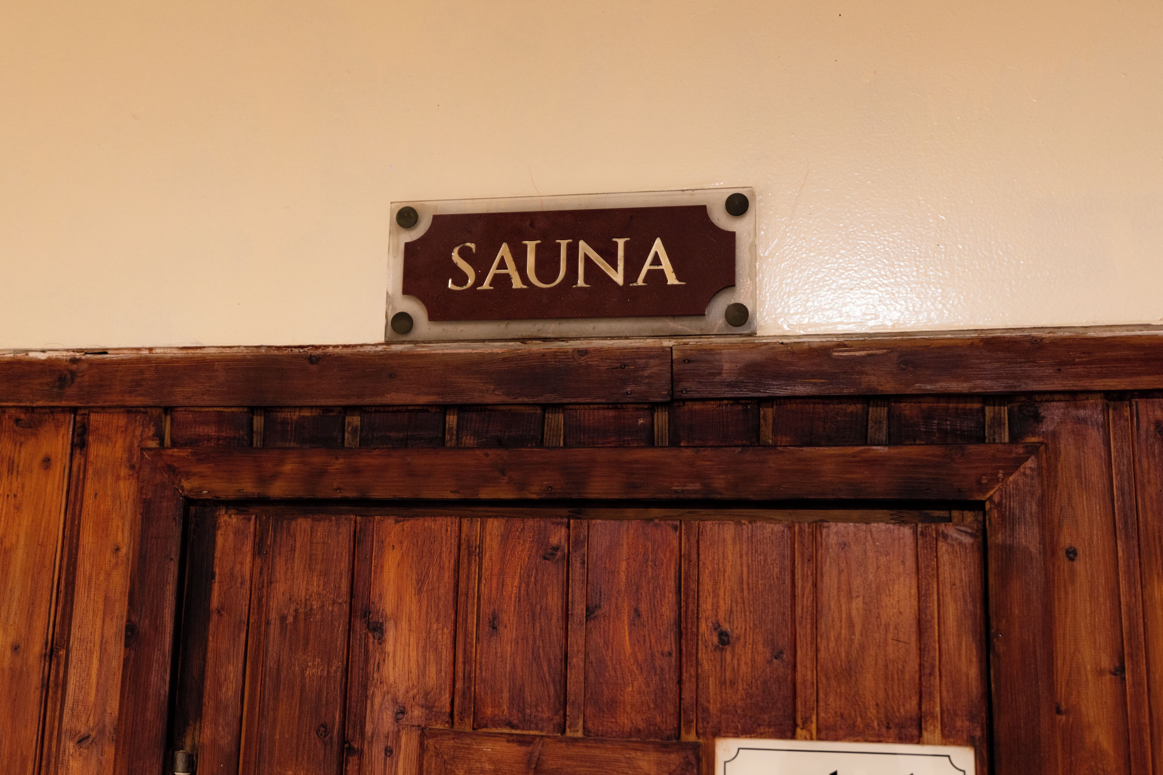 Een houten wand met een bord waarop 'SAUNA' staat.