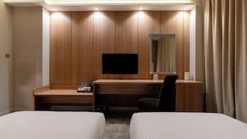 Une chambre d’hôtel avec deux lits, un bureau avec une télévision et un miroir.