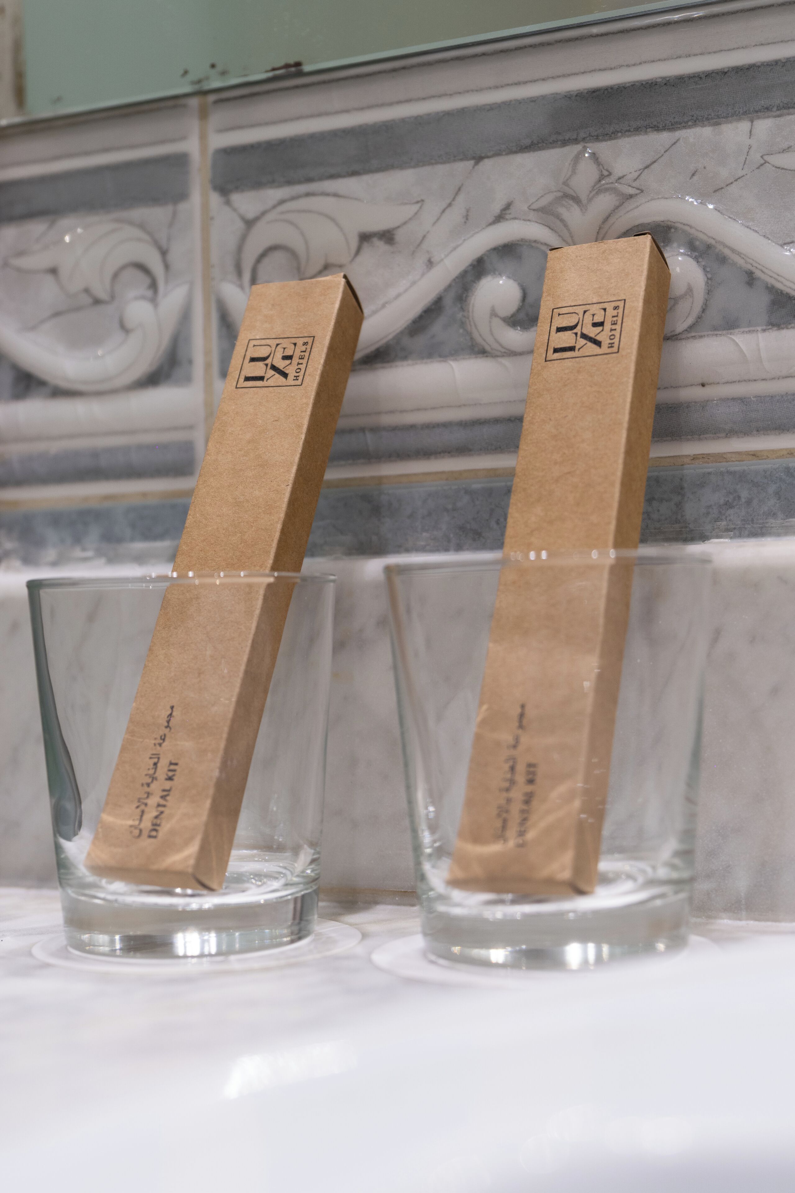 Two glasses with brown paper labels on a marble surface.