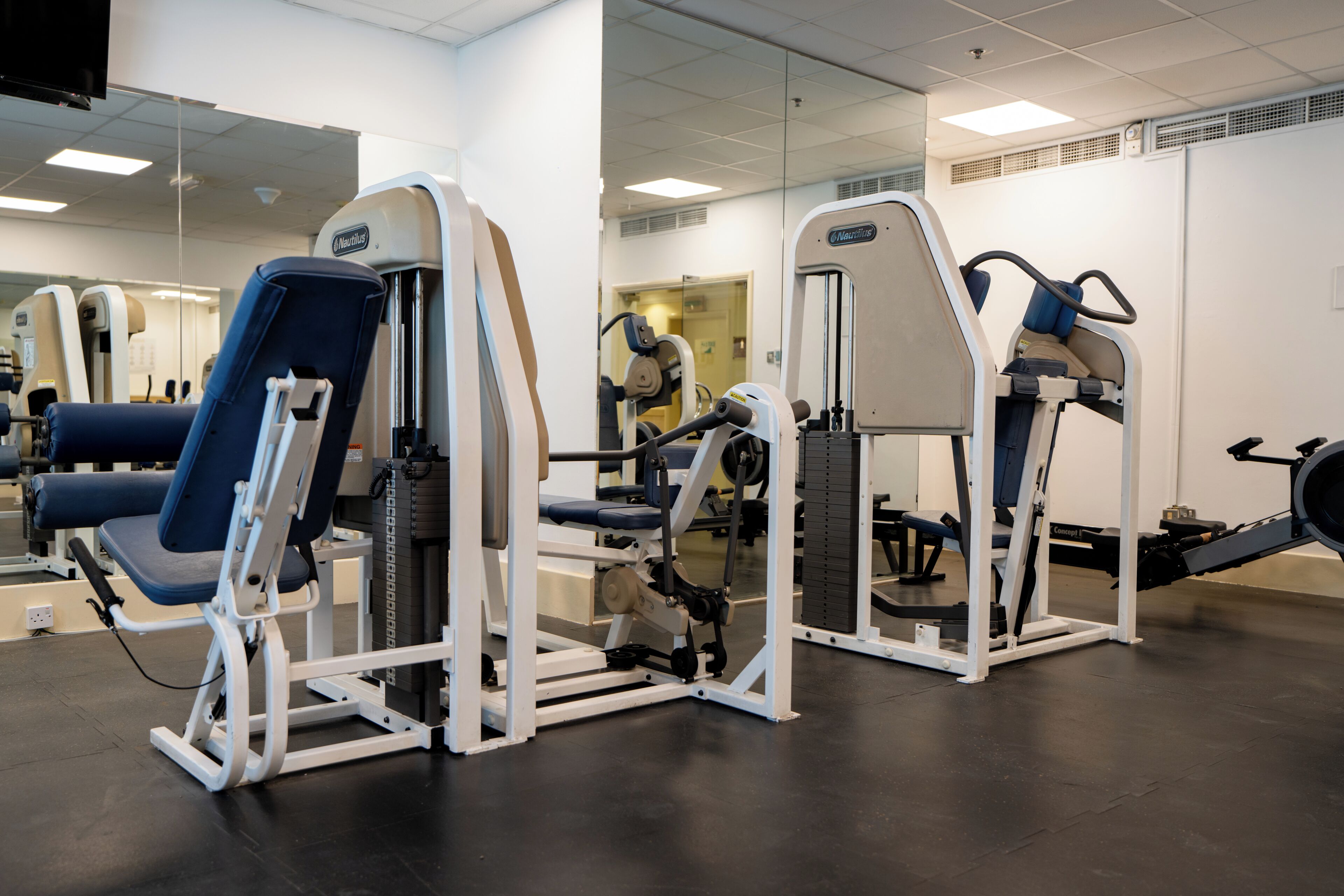 A gym with exercise equipment, a mirror, and a ceiling-mounted television.