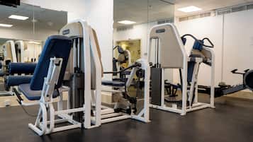 A gym with exercise equipment, a mirror, and a ceiling-mounted television.