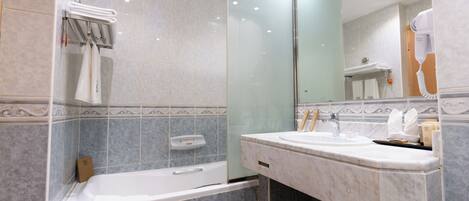 Une salle de bain moderne avec une douche à parois de verre, une baignoire, un lavabo en marbre et un grand miroir.