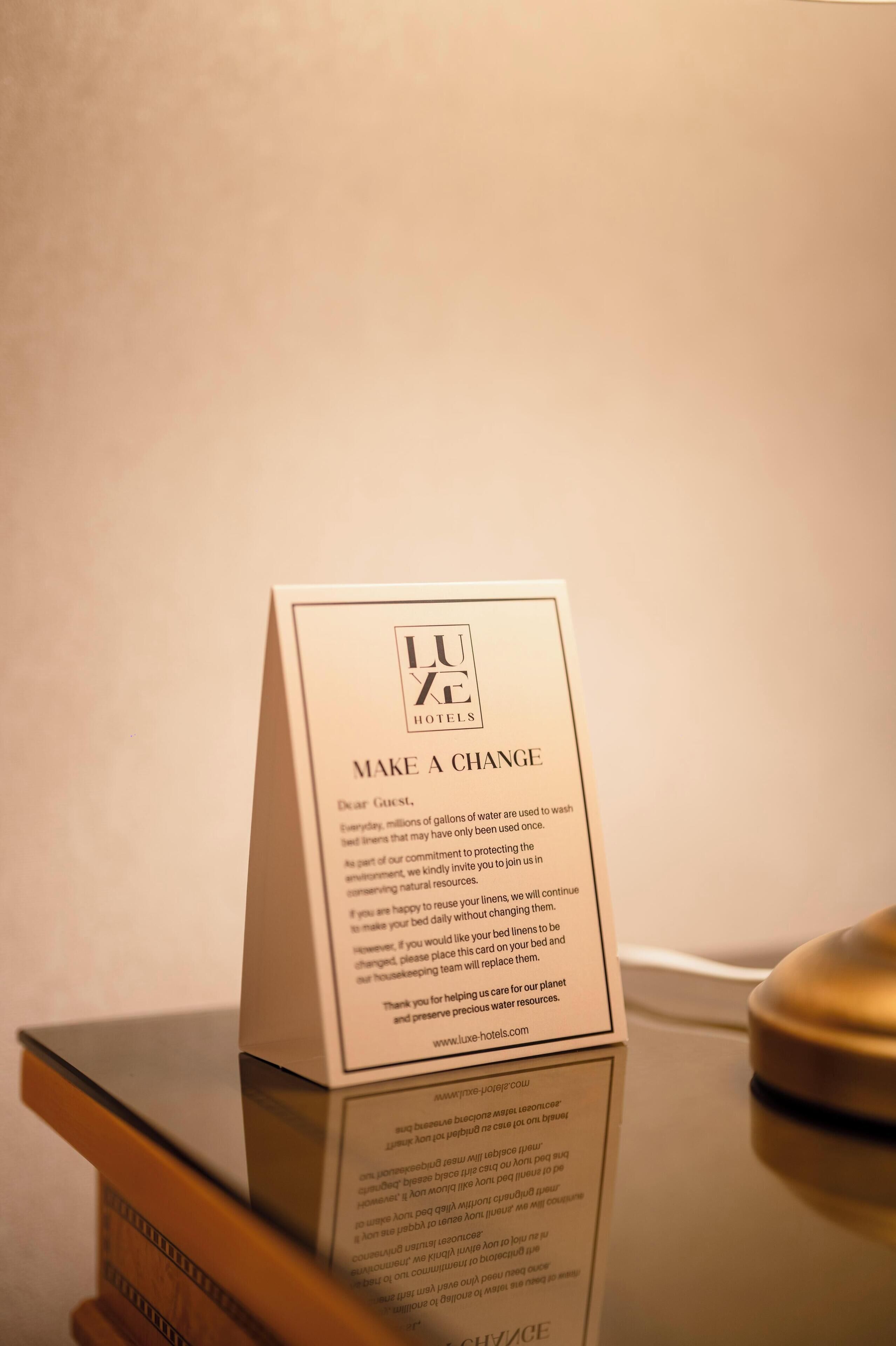 A hotel sign with the text "LUKE X HOTELS MAKE A CHANGE" and a message about water conservation.
