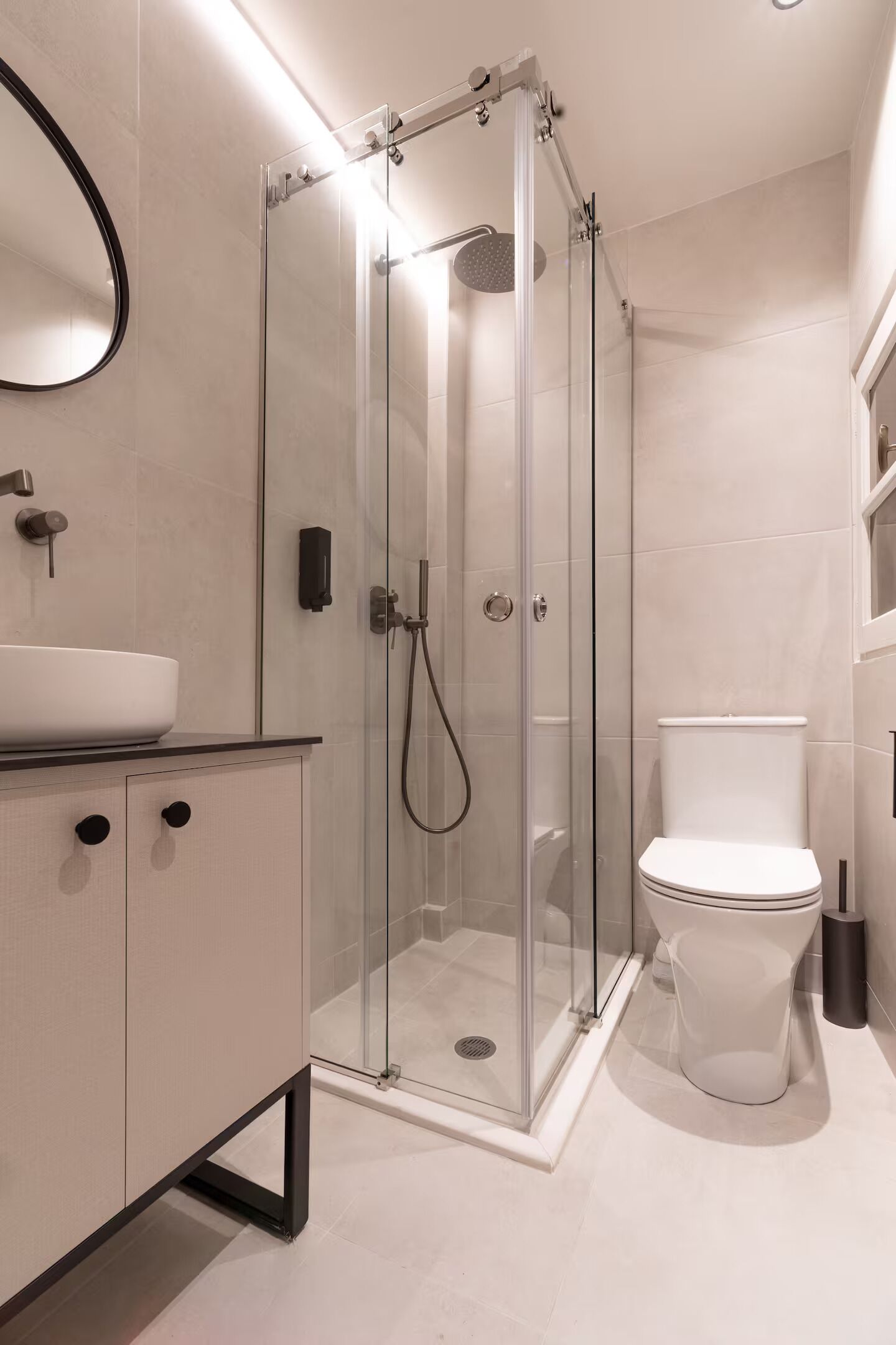 A modern bathroom with a glass-enclosed shower, a white sink, and a toilet.
