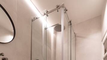A modern bathroom with a glass-enclosed shower, a white sink, and a toilet.