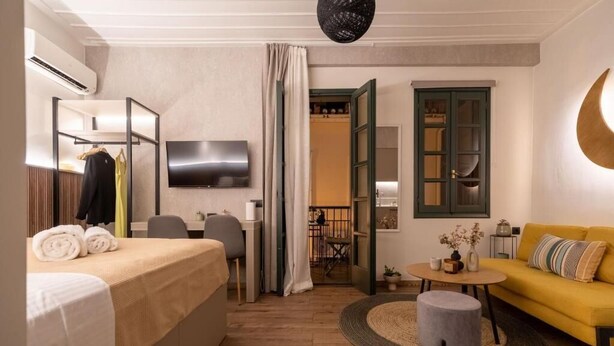 Et moderne hotelværelse med seng, sofa, TV og spiseplads.