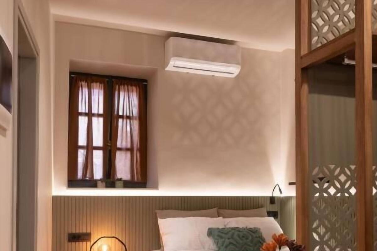 A bedroom with a bed, bedside table, and a window with curtains.