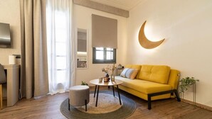En moderne stue med en gul sofa, et rundt sofabord og en grå skammel.