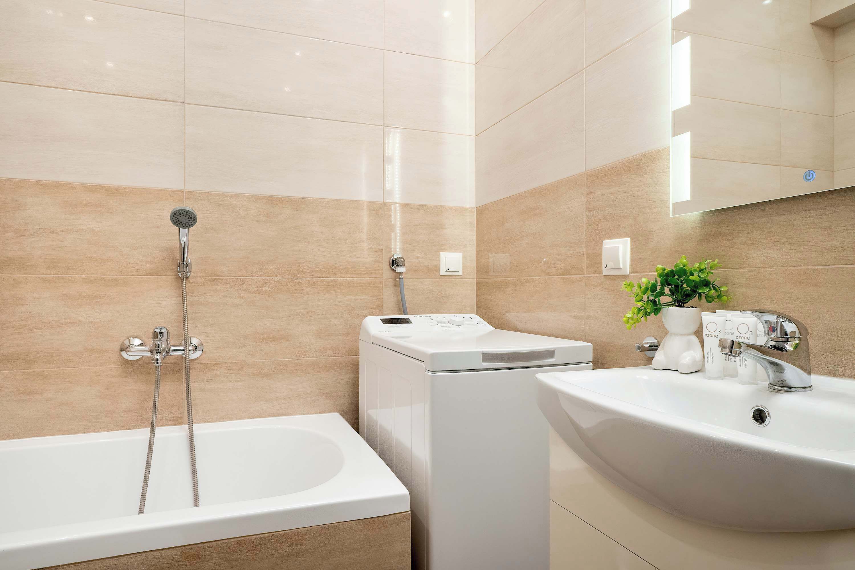 A bathroom with a bathtub, a washing machine, and a sink with a mirror above.
