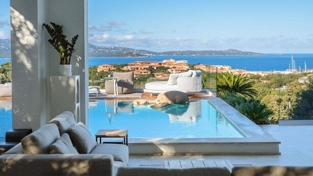 Ein moderner Infinity-Pool mit freiem Blick auf das Meer und eine Küstenstadt.