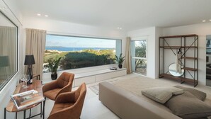 Ein modernes Schlafzimmer mit großem Fenster, einer Couch, einem Couchtisch und einem Bücherregal.