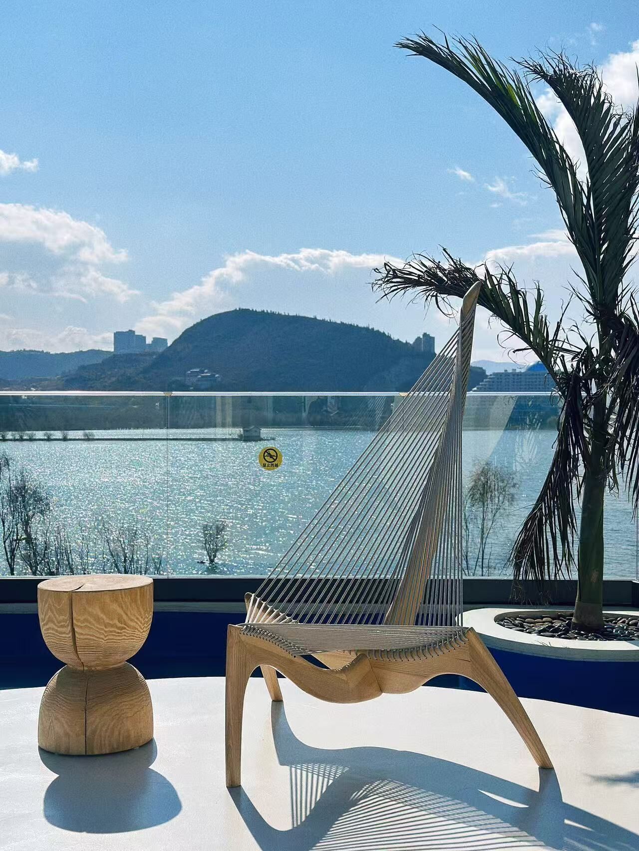 A hammock chair by a window overlooking a body of water with a mountain in the background.