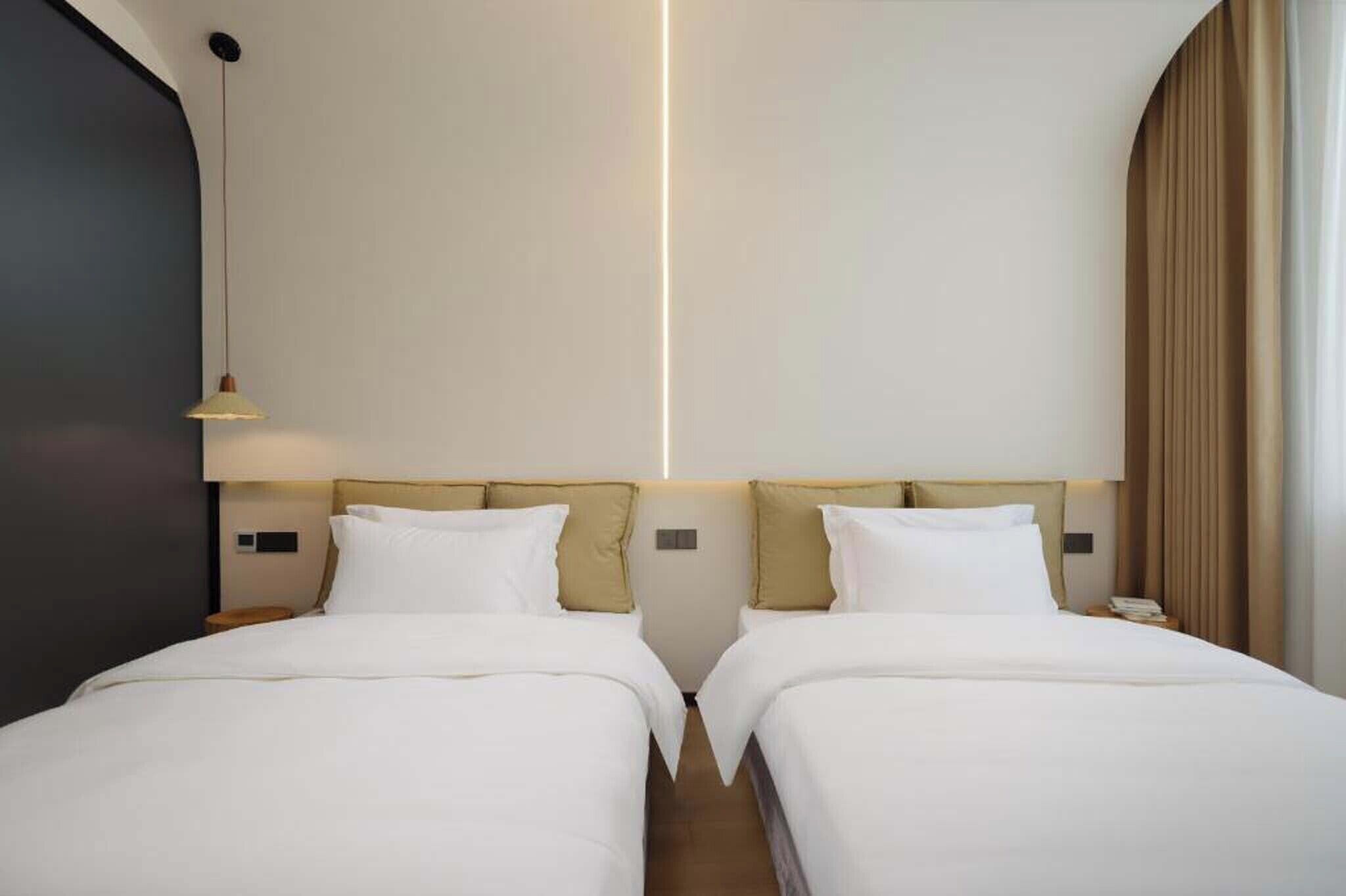 Een hotelkamer met twee bedden, een modern design en een groot raam met gordijnen.