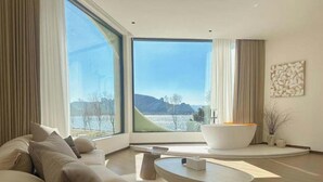 A modern living room with a large window, a sofa, a coffee table, and a bathtub. - Dali Fanxi Manhai Holiday Guesthouse (Dali)