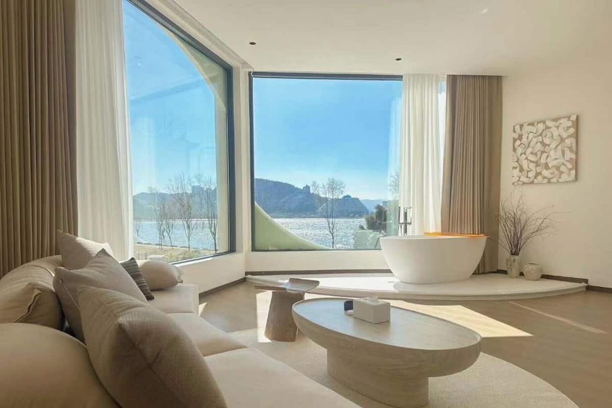 Ein modernes Wohnzimmer mit großem Fenster, einer Couch, einem Couchtisch und einer Badewanne.
