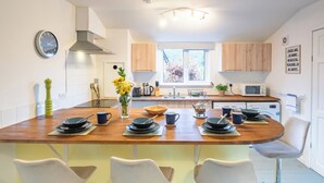 A modern kitchen with a central island, wooden cabinets, a built-in microwave, and a window providing natural light. - The Chalet by Interhome (Fort Augustus)