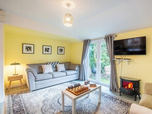 Una sala de estar con un sofá, una mesa de ajedrez, un televisor y una chimenea.