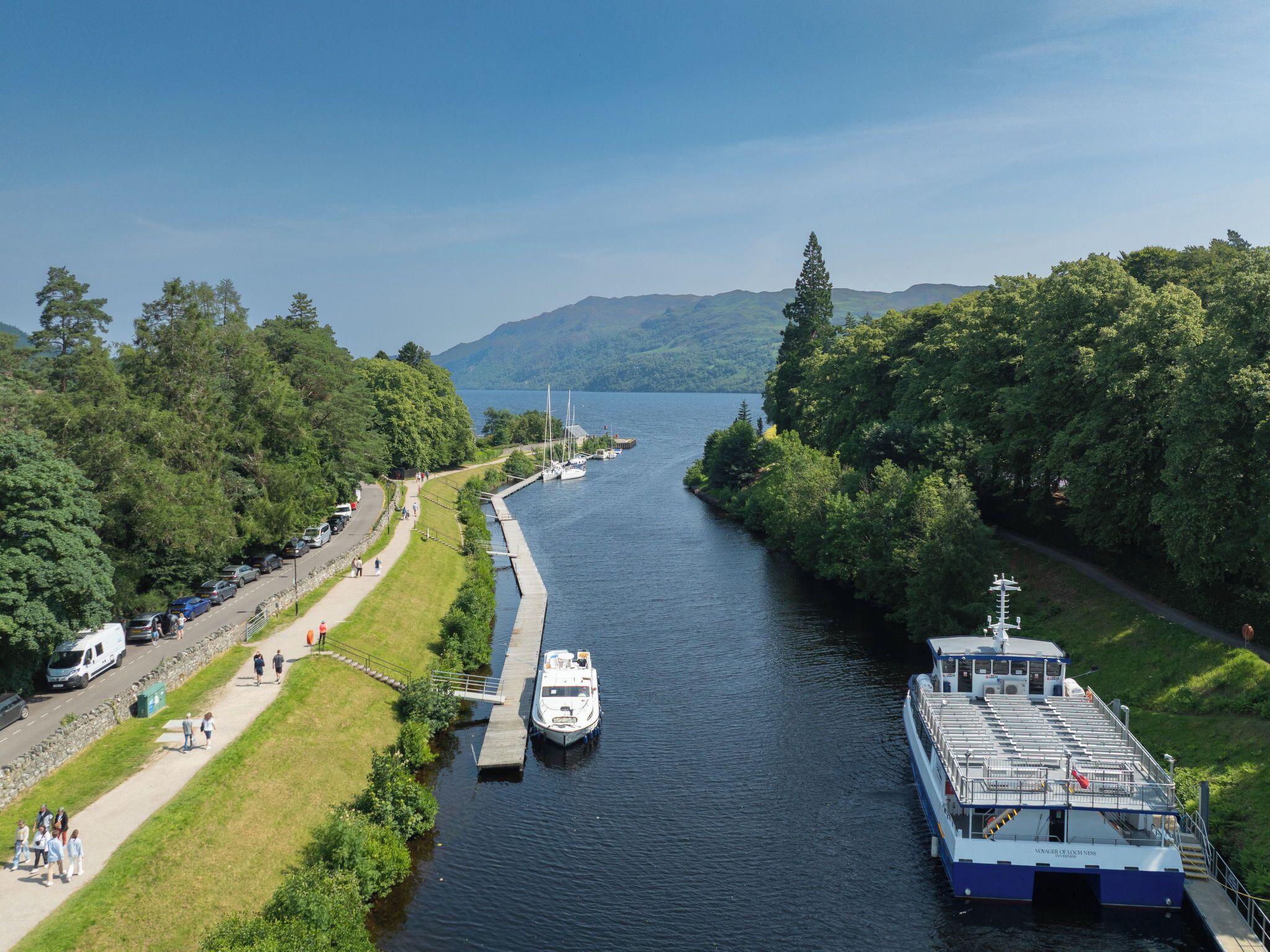 A river with boats docked, a dock, and a pathway alongside.