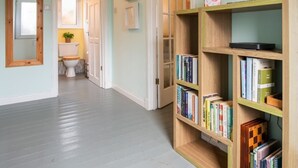 A hallway with a wooden bookshelf, a door leading to a bathroom, and a light fixture on the ceiling. - The Chalet by Interhome (Fort Augustus)