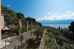 A stone pergola with a barbecue area overlooking a lake.