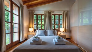 A hotel room with a large bed, two bedside tables with lamps, and a view of greenery through large windows. - Luxury 7BR Villa | Private Pool & Lake Garda View | Limonaia dei Dogi | Gargnano (Gargnano)