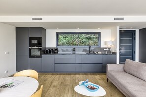 Une cuisine moderne avec des meubles gris, un four à micro-ondes encastré et une fenêtre donnant sur un espace verdoyant.