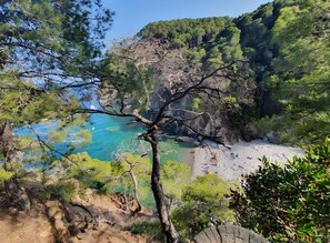 Un paysage côtier caractérisé par des falaises rocheuses, une eau d’un bleu limpide et une plage de sable.