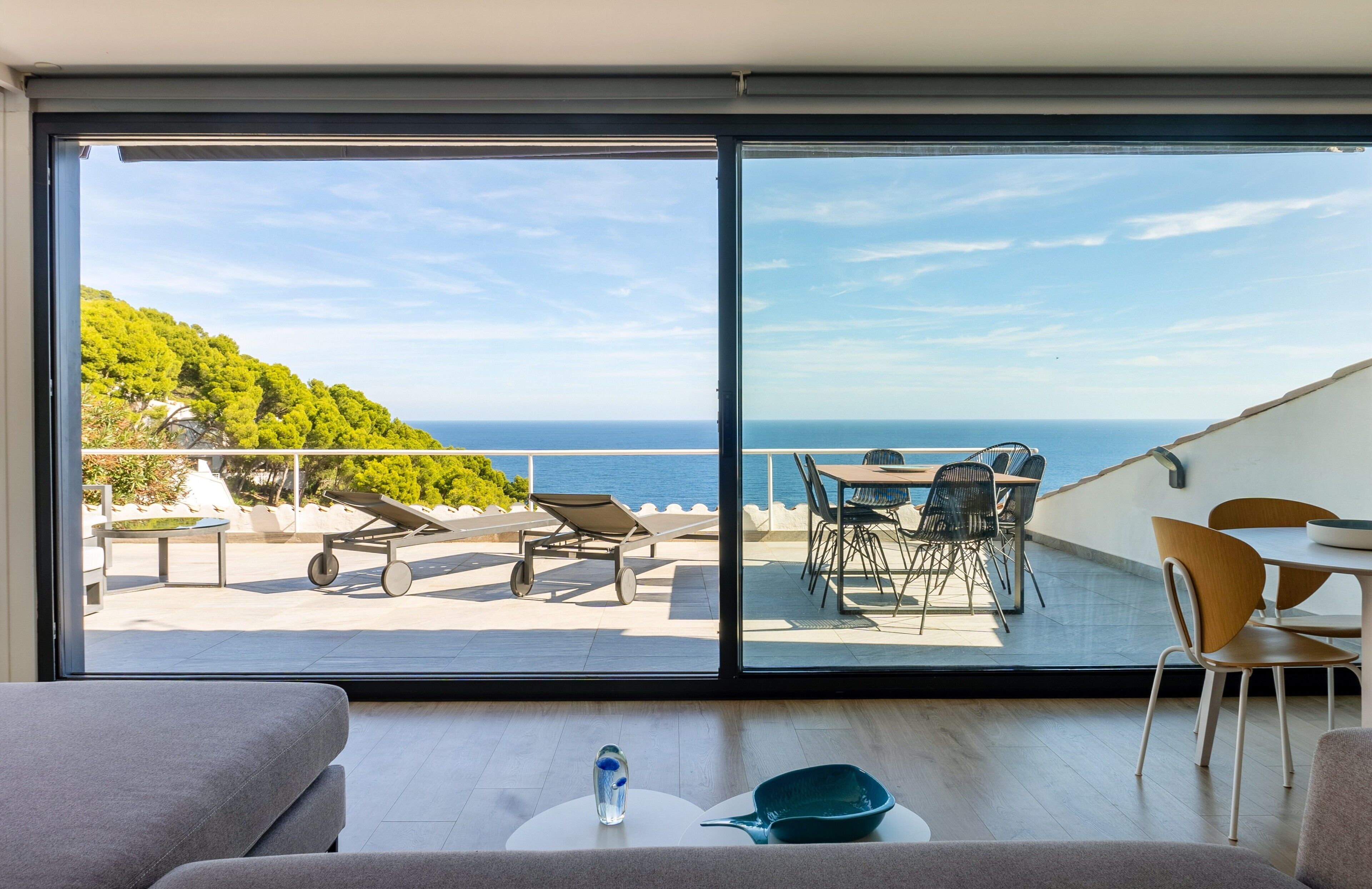 A balcony with a table, chairs, and a view of the sea.