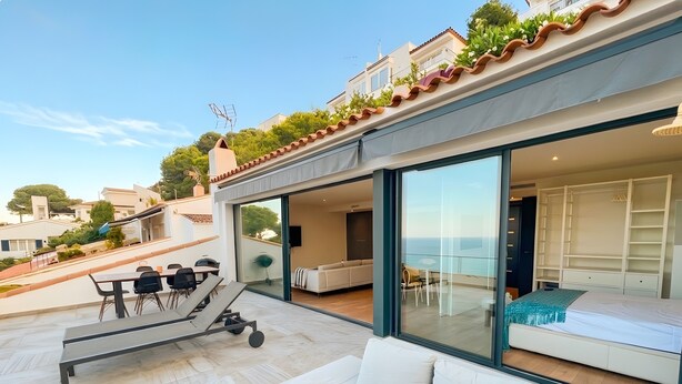 Een moderne villa met een terras, buitenmeubels en uitzicht op zee.