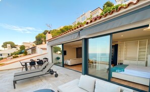 Una villa moderna con patio, mobiliario exterior y vistas al mar.