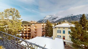 A view of a multi-story building with balconies, a snow-covered roof, and a mountain backdrop. - Spacious 3-Bedroom Apartment with Balcony & Mountain Views in Champfèr (Champfèr)