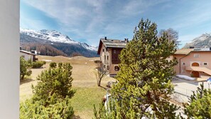 Eine Berglodge mit Holzfassade, einem Balkon und Blick auf schneebedeckte Berge.