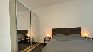 Une chambre à coucher avec un grand lit, des lampes de chevet, une armoire avec un miroir et une tête de lit.