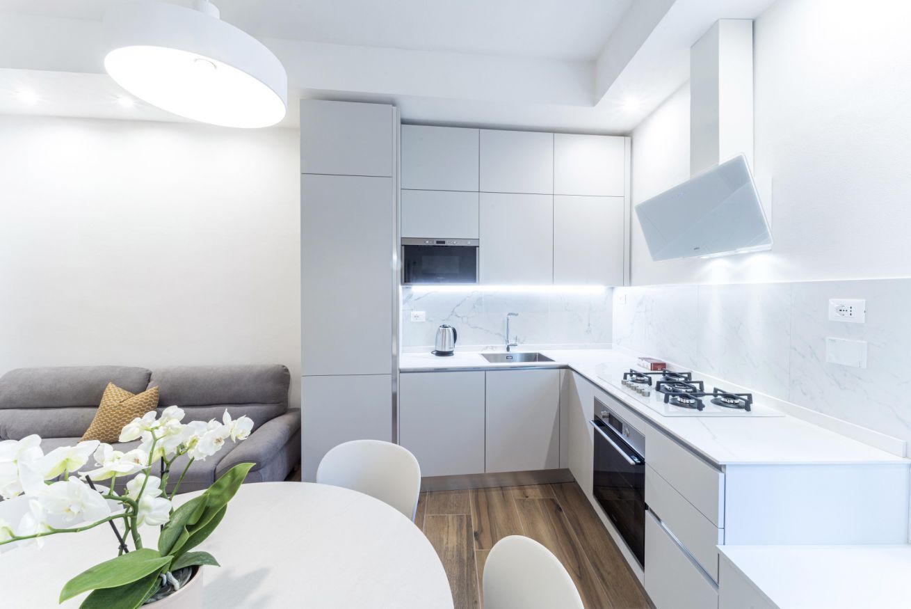 A modern kitchen with white cabinets, a built-in oven, and a microwave.