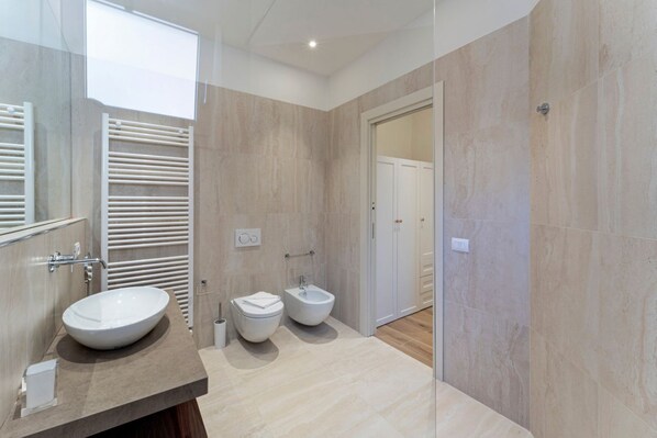 Ein modernes Badezimmer mit einem großen Spiegel, zwei Waschbecken, einem Bidet und einer Toilette.