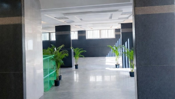 A spacious indoor area with a modern ceiling design, large windows, and potted plants. - Truliv Luna (Bengaluru)