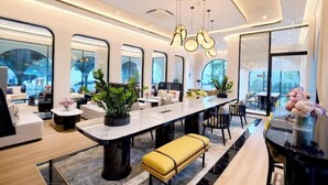 Un intérieur moderne avec une longue table à manger, de nombreuses chaises et des plantes en pot.