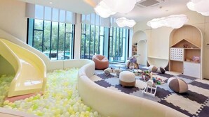 Un espace de jeux pour enfants avec un toboggan, une piscine à balles et divers jouets.