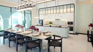 Une cuisine moderne dotée d’un îlot central, d’appareils électroménagers intégrés et d’un coin repas avec une longue table et des chaises.