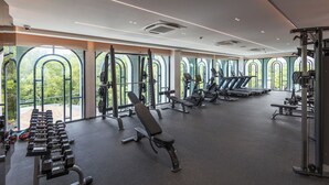 Une salle de sport moderne dotée de divers équipements d’exercice, de grandes fenêtres et d’un aménagement spacieux.
