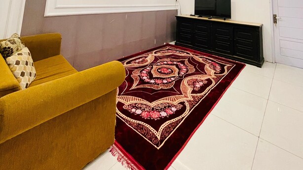 Una sala de estar moderna con iluminación empotrada en el techo, un tapete estampado, un sofá amarillo y un mueble de entretenimiento negro.