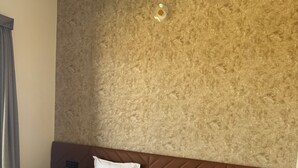Une chambre d’hôtel avec un grand lit, une table de chevet et un luminaire fixé au mur.