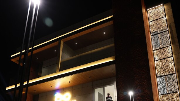 Un bâtiment moderne, doté d'une enseigne lumineuse bien visible, d'une entrée bien éclairée et d'un mur orné de motifs.