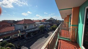 A balcony with a view of a street and buildings. - Famora Stay Kuta Bali (Kuta)