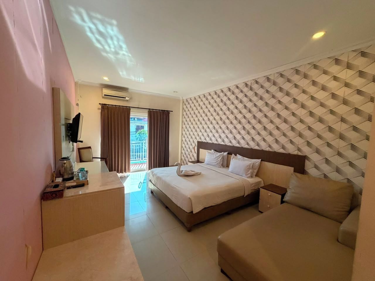 Habitación de hotel con cama, sofá, escritorio y tetera, y televisor.