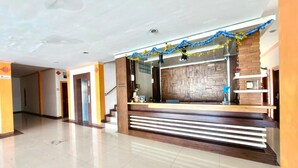 A spacious lobby with a reception desk, a staircase, and a decorative garland. - Famora Stay Kuta Bali (Kuta)